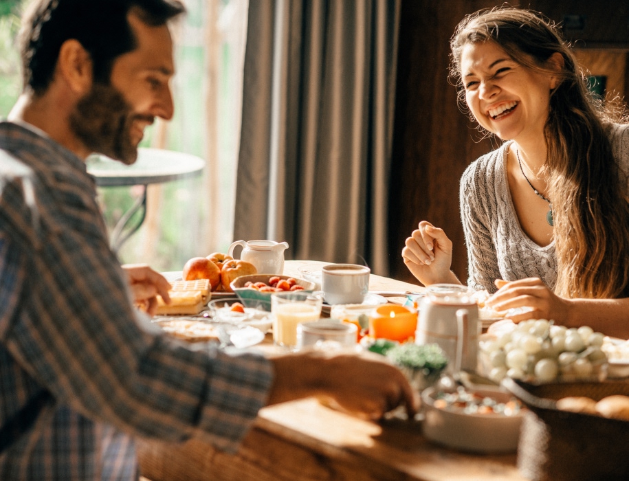 young couple sitting at a table with a variety of food